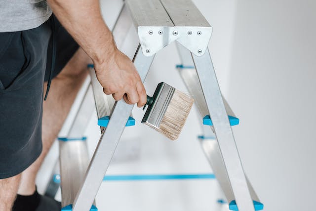 person-climbing-on-a-ladder-with-a-paint-brush person-climbing-on-a-ladder-with-a-paint-brush