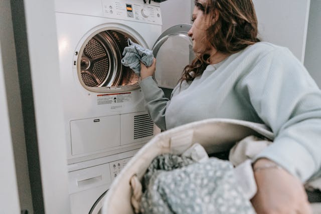 person-holding-a-laundry-hamper-putting-clothes-into-the-washing-machine person-holding-a-laundry-hamper-putting-clothes-into-the-washing-machine