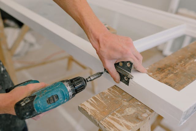 person-using-an-electric-drill-to-install-door-hinges person-using-an-electric-drill-to-install-door-hinges