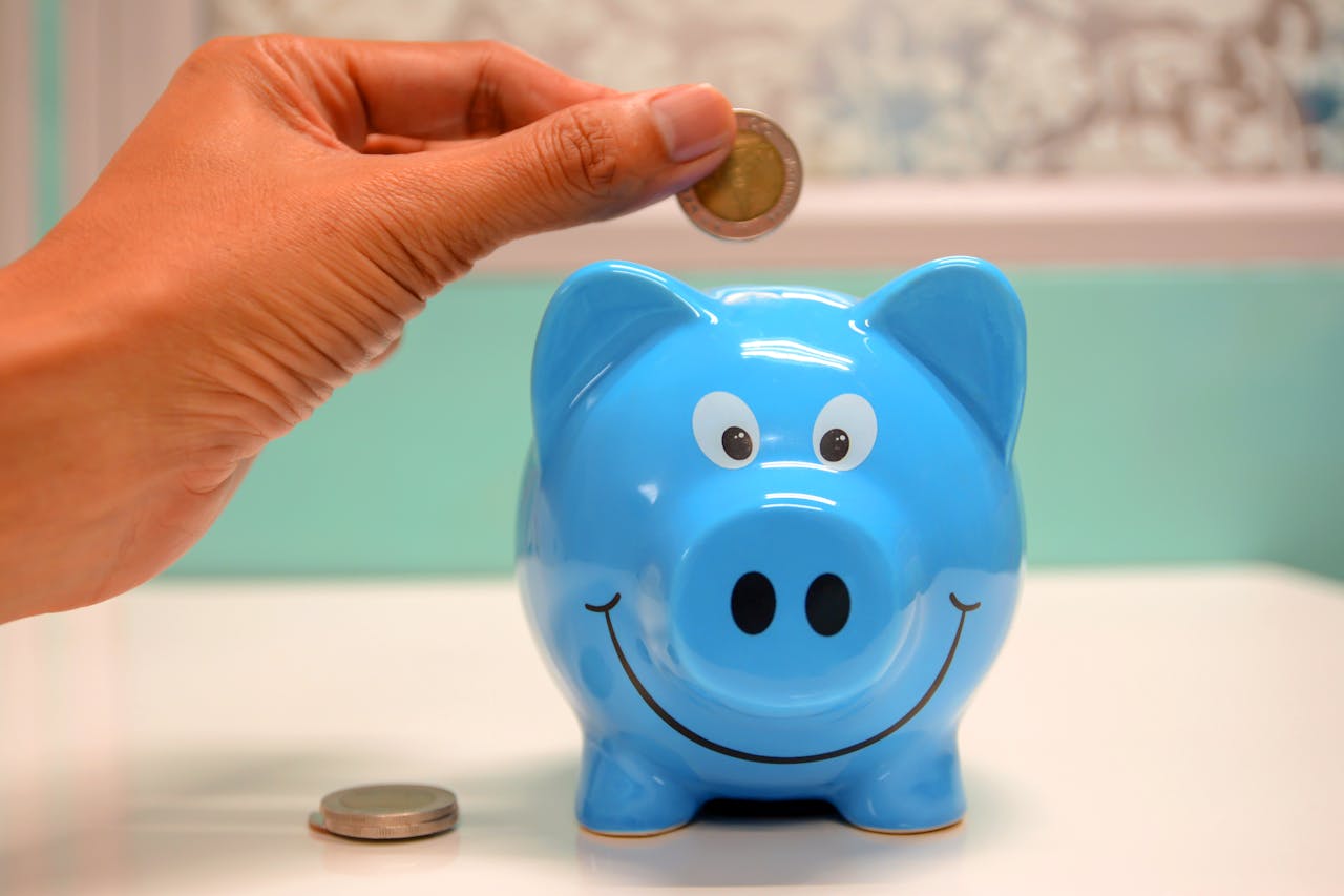 coin-being-put-in-blue-piggy-bank coin-being-put-in-blue-piggy-bank