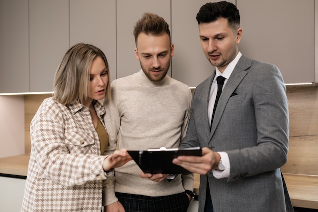 property-manager-looking-at-a-document-on-a-clipboard-with-two-people property-manager-looking-at-a-document-on-a-clipboard-with-two-people