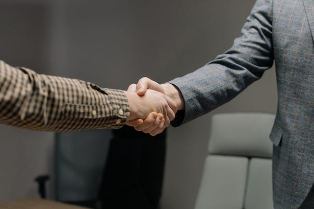 two-people-shaking-hands-in-business-clothing two-people-shaking-hands-in-business-clothing