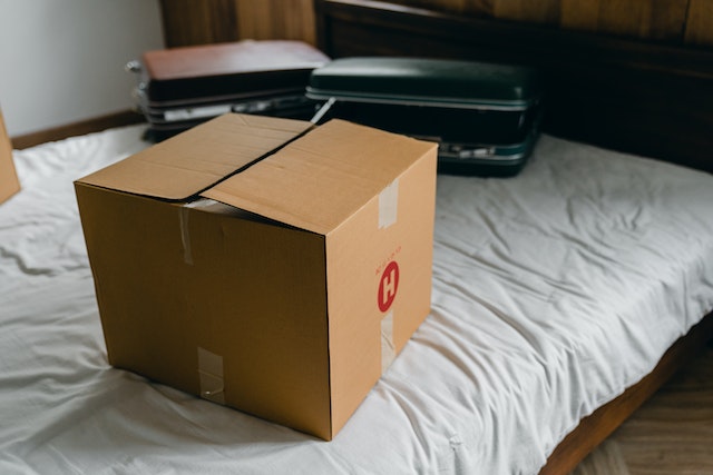 a-moving-box-and-suitcases-sitting-on-a-bed a-moving-box-and-suitcases-sitting-on-a-bed