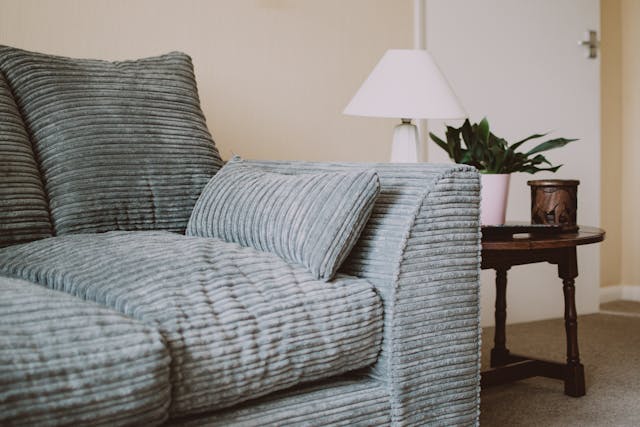 pexels-fotios-photos-1631918 a light blue-grey couch with a side table